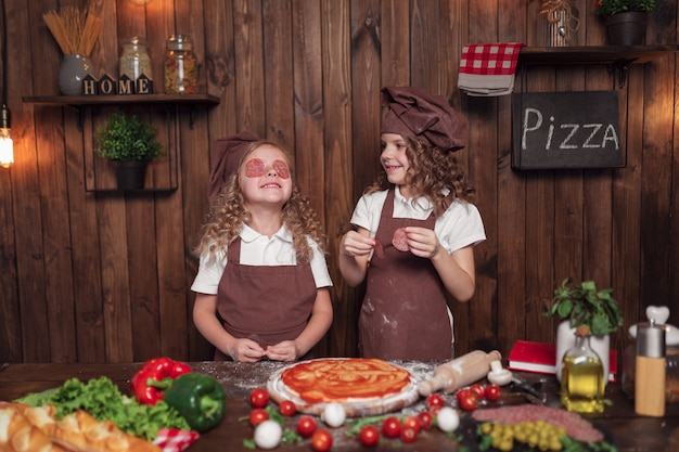 Alegres garotas se divertindo com salsicha na cozinha