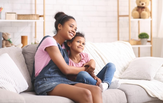 Alegres hermanas africanas abrazándose en casa espacio libre