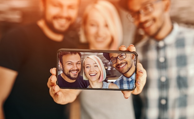 Alegres hombres y mujeres multirraciales tomando selfie