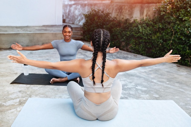 Alegres jovens mulheres árabes afro-americanas atletas em roupas esportivas praticam exercícios respiratórios de ioga