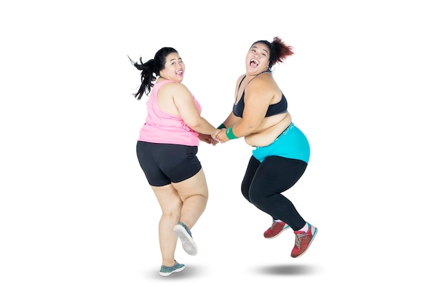 Alegres mulheres com sobrepeso pulando no estúdio
