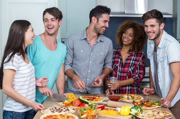 Alegres multi étnica amigos preparando pizza em casa