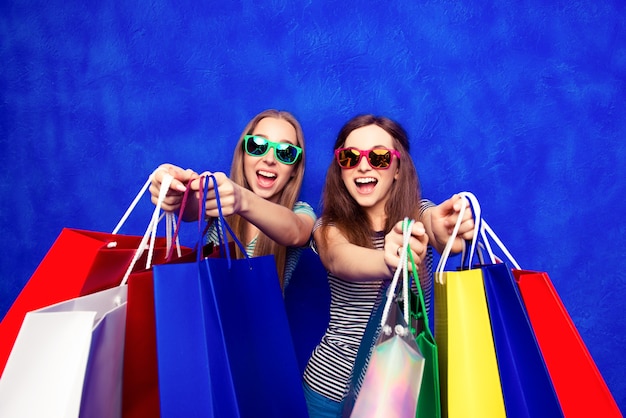 Alegres niñas sonrientes en espectáculos mostrando sus compras