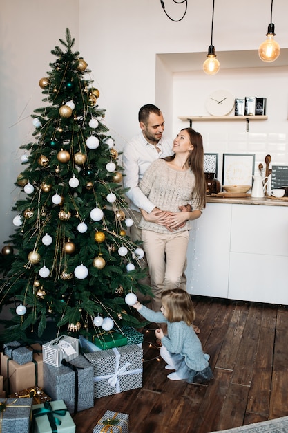 Alegres padres y su linda hija esperando la Navidad en casa