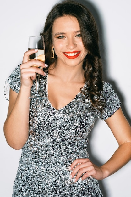 Alegria de festa mulher feliz celebração de aniversário olhar festivo senhora sorridente elegante em vestido prata lantejoula segurando a taça de champanhe posando branco isolado