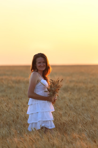 Alegria de menina no campo de trigo na hora do pôr do sol