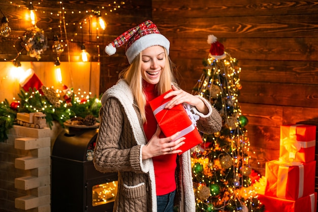 Alegría navideña. Luces de guirnalda de adornos navideños interiores de madera de mujer. Árbol de Navidad. Lleno de alegría, alegría y amor. Chica disfruta de un ambiente acogedor en la víspera de Navidad. Navidad. Momentos agradables.