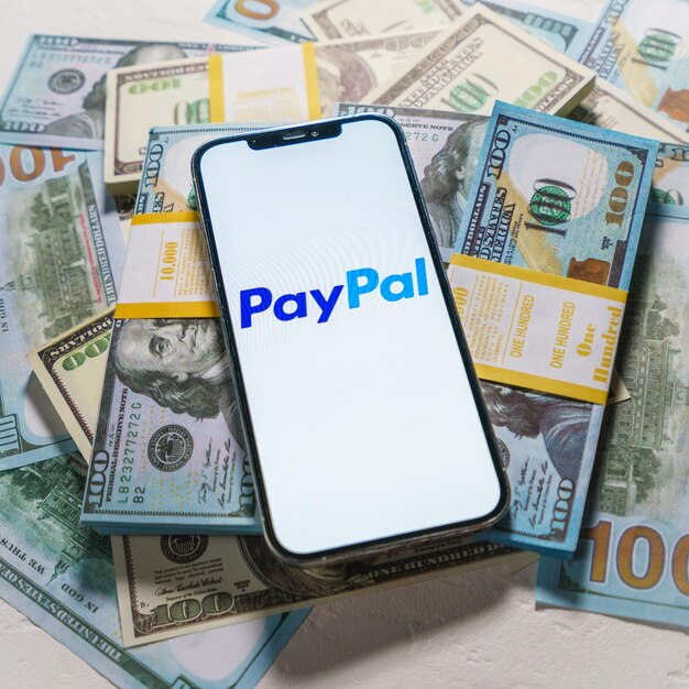 Alemanha 02 de fevereiro de 2022 iPhone 12 Pro Max com ícone Paypal em fundo de moeda de dólar Paypal é um serviço de transferência de dinheiro digital baseado na internet