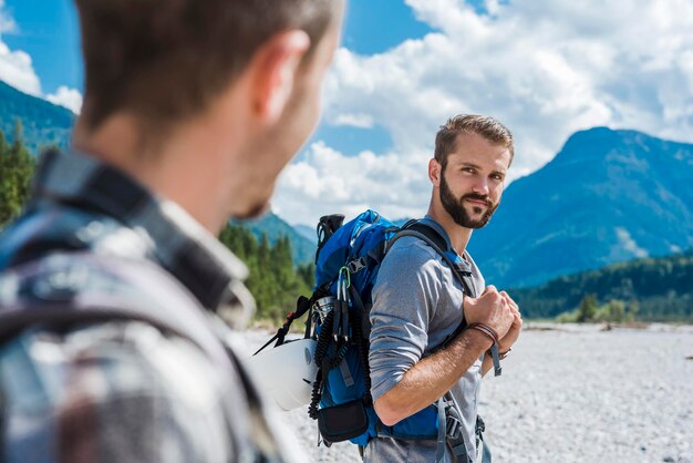 Alemanha, Baviera, retrato de jovem alpinista com mochila olhando para seu amigo