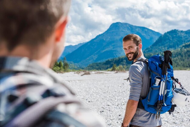 Alemanha, Baviera, retrato de jovem alpinista com mochila olhando para seu amigo