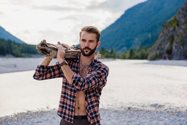 Alemanha, Baviera, retrato de jovem carregando lenha no ombro na natureza