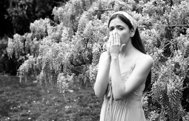 Alergia de primavera Niña con estornudo en la nariz Concepto de síntomas alérgicos Mujer alérgica a las flores al aire libre