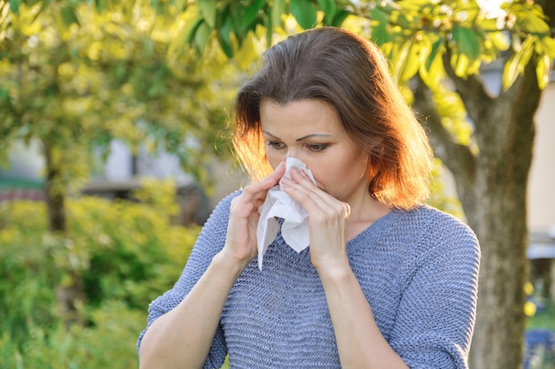 Alergias sazonais, mulher com limpeza nasal, espirros, limpando o nariz ao ar livre