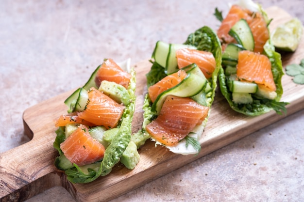 Alface embrulhada em tacos de salmão defumado com pepino fresco, abacate e ovos de codorna