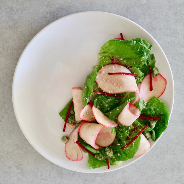 Foto alface esmagada e salada de rabanete vermelho fatiado no prato.