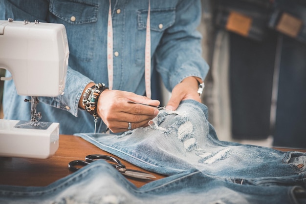 Foto alfaiate a trabalhar com calças jeans