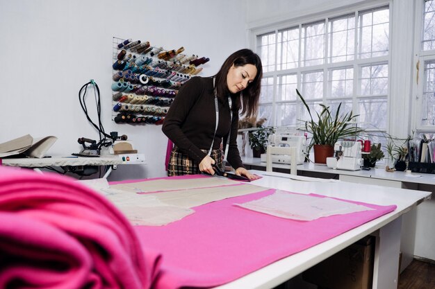 Alfaiate de designer de moda feminina fazendo padrões de costura no local de trabalho no estúdio de costura