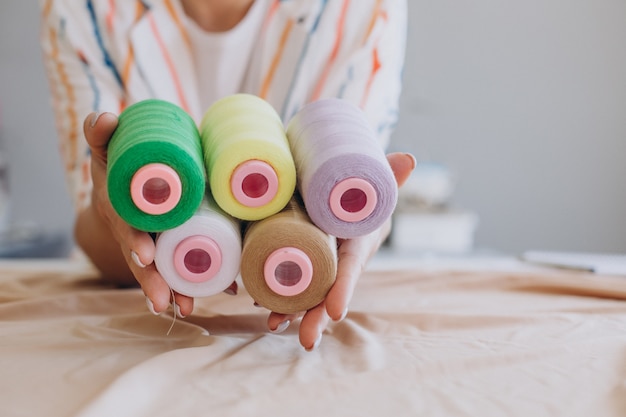 Alfaiate feminina segurando rolos de linha