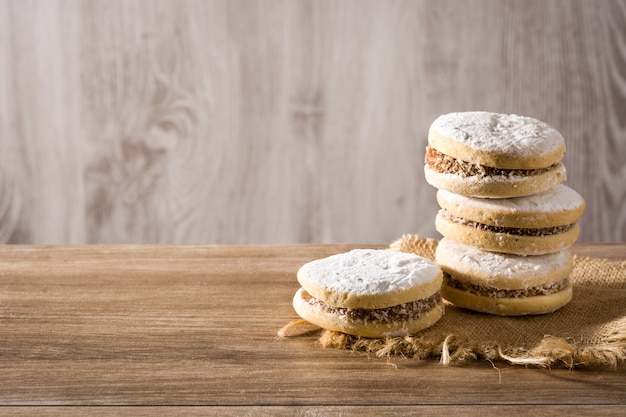 Alfajores argentinos tradicionales con dulce de leche y azúcar en la mesa de madera, espacio de copia