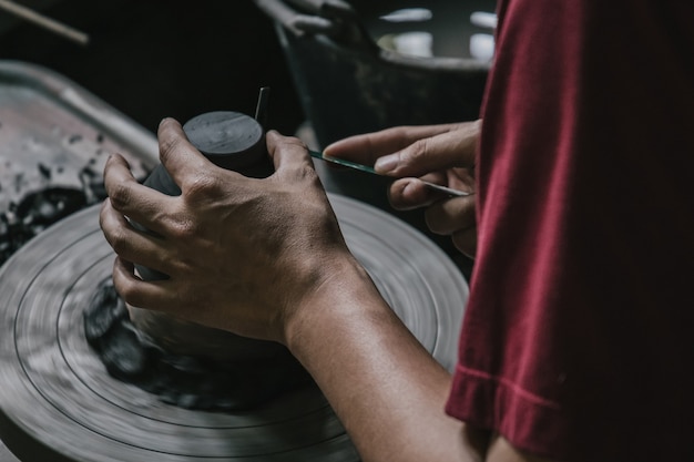 Alfarero artesano profesional asiático haciendo artesanía en maceta o jarrón en rueda en taller de taller de cerámica.