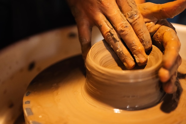 Alfarero artesano profesional haciendo jarra de arcilla en círculo de rueda de alfarero en taller