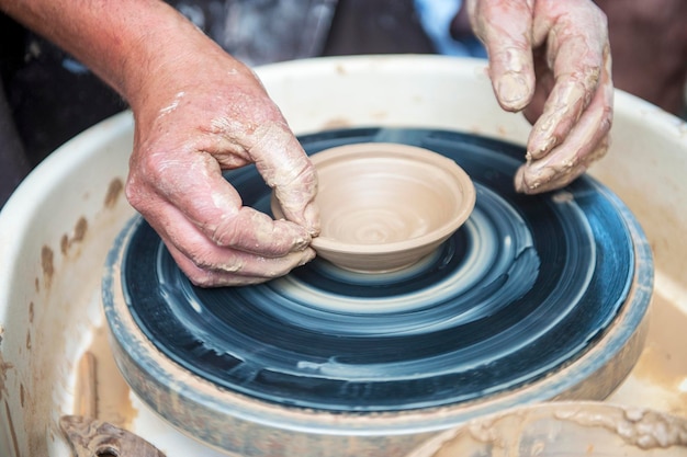 El alfarero hace platos de cerámica en el torno de alfarero El escultor en el taller hace primer plano del producto de arcilla Manos del alfarero