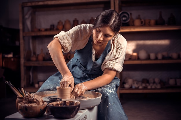 Alfarero profesional con estilo haciendo cerámica de arcilla húmeda en la rueda