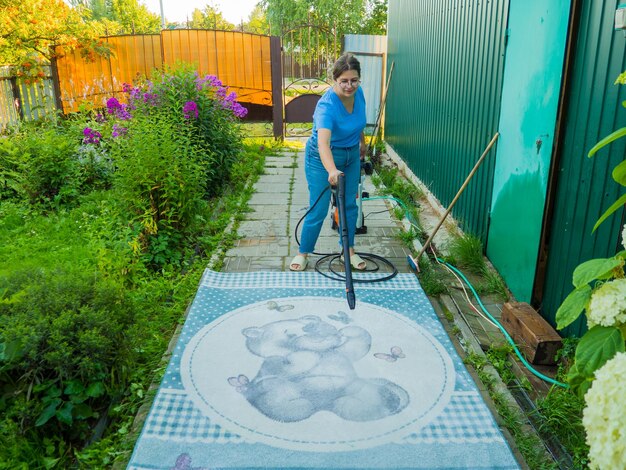 Alfombra lavable a presión Limpieza de alfombras con un spray profesional una niña lava alfombras en la calle