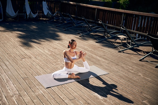 En la alfombra de yoga Una joven con ropa de fitness está al aire libre