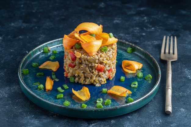 Alforfón hervido con huevos fritos, pimientos rojos, zanahorias y cebollas, de cerca, Ucrania. Fondo de alimentos. Comida sana