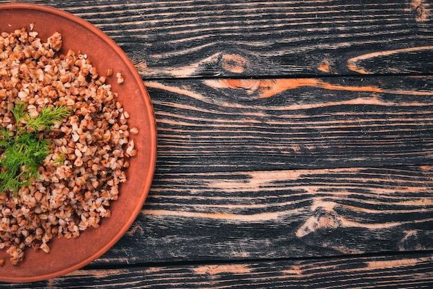 Alforfón en un plato. Sobre un fondo de madera. Vista superior. Copie el espacio.