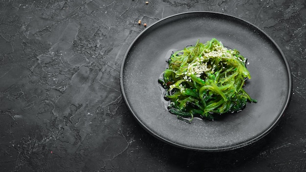 Algensalat in einem schwarzen Teller Chuka Wakame Auf dem alten Hintergrund Draufsicht Freier Platz für Ihren Text