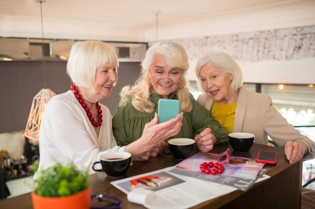 Algo animado. Mulheres parecendo animadas enquanto assistem algo em um smartphone