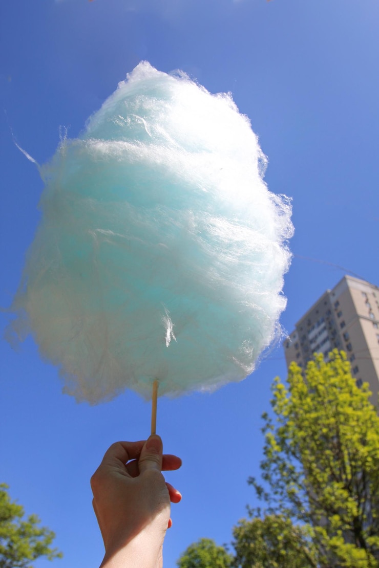Foto algodón de azúcar en la mano sobre el fondo del cielo azul