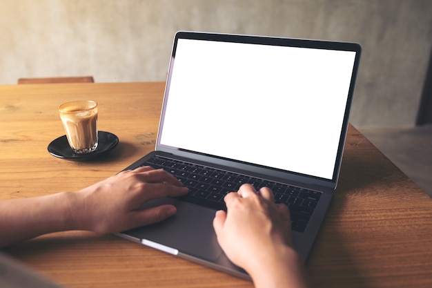 Alguém está usando laptop, com uma xícara de café na mesa de madeira