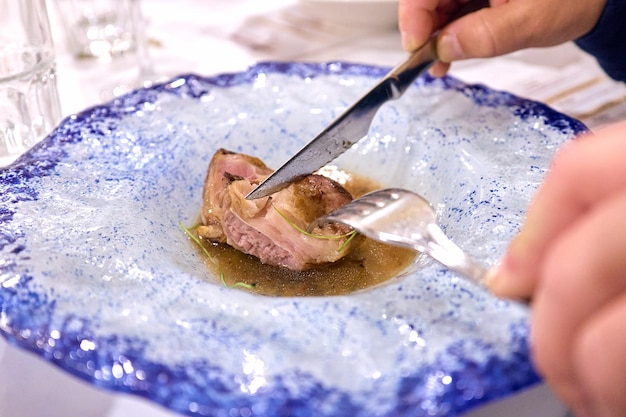 Alguien cortando un trozo de costilla de res en un plato no se muestran caras