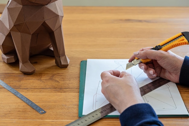 Alguien está haciendo una escultura de cubo con papel lineal y cuchillo DIY