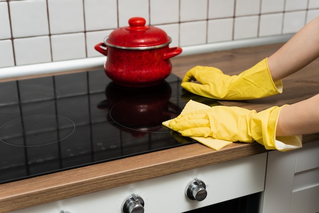 Foto alguien está lavando una estufa de cocina con guantes amarillos. alguien está limpiando una cocina con un trapo.