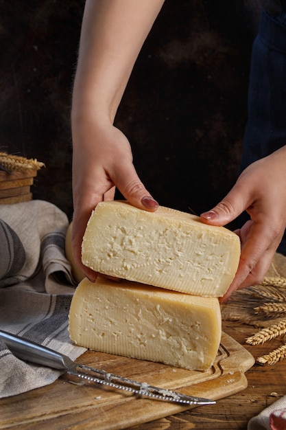 Alguien manos poner trozos de queso casero fresco sobre una tabla de madera de cerca