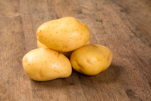 Algumas batatas sobre uma superfície de madeira. Vegetais frescos.