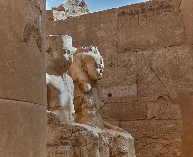 Algumas grandes estátuas sentadas na frente de um edifício no templo