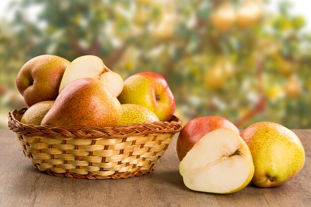 Algumas peras em uma cesta sobre uma superfície de madeira. Frutas frescas