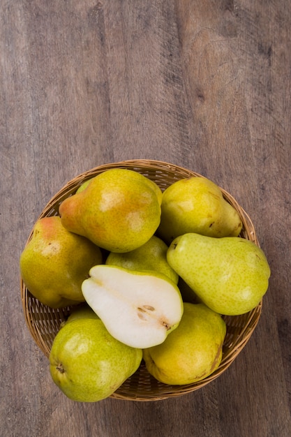 Algumas peras em uma cesta sobre uma superfície de madeira. Frutas frescas