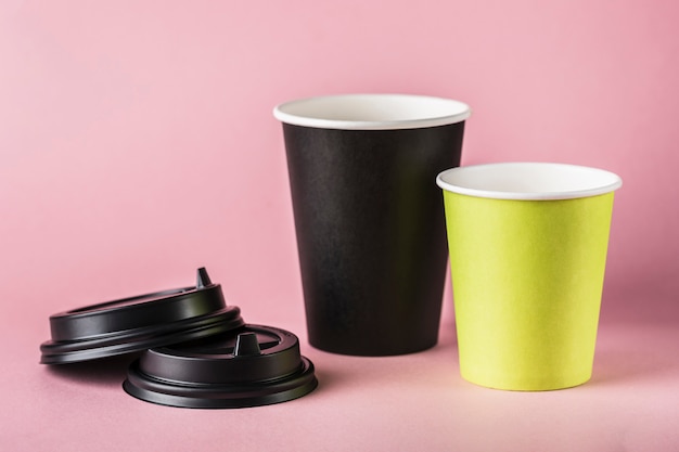 Algumas xícaras de café reutilizáveis de papel verde e preto com tampas.