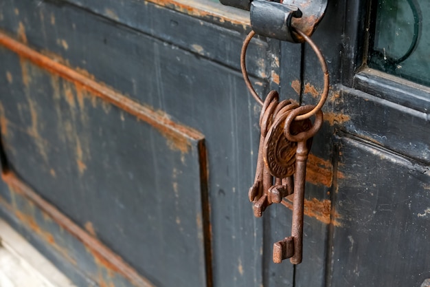 Algunas cadenas de llaves viejas y oxidadas en una puerta rústica