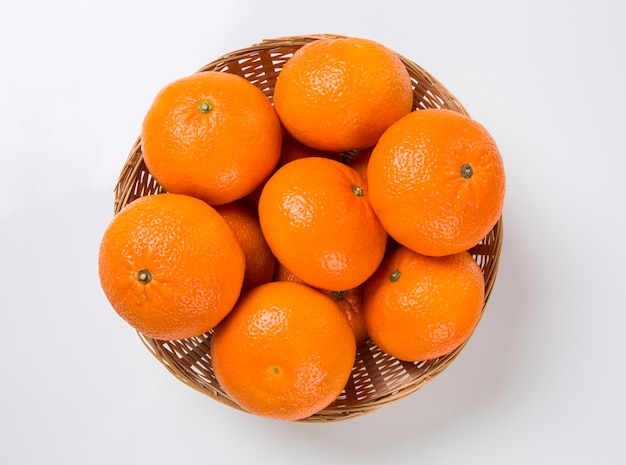 Algunas mandarinas en una canasta sobre una superficie blanca. Frutas frescas.