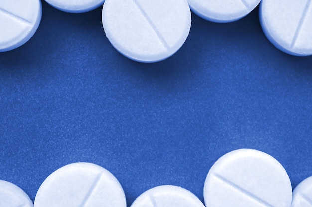 Algunas tabletas blancas yacen sobre una superficie de fondo de color azul clásico fantasma brillante Imagen de fondo sobre temas médicos y farmacéuticos