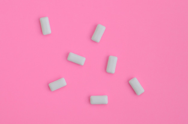 Algunos chicles se encuentran en el fondo de textura de papel de color rosa pastel de moda en un concepto mínimo