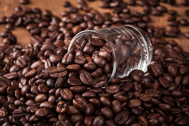 algunos grano de café en vaso de café montón de frijoles en la mesa de madera