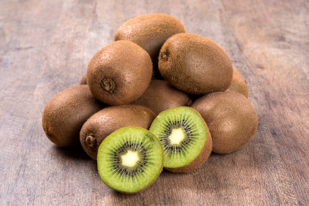 Algunos kiwis en una canasta sobre una superficie de madera. Frutas frescas